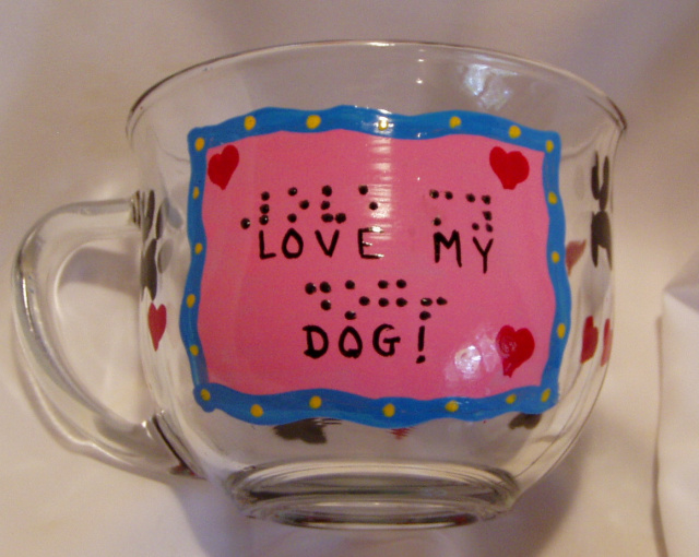  "Love My Dog"- 14 oz.  glass mug. Painted label with standard blue or pink (or choose your favorite color!) background, "Love My Dog" written in script and in braille. Mugs have paw prints and red hearts around the rest of the mug.