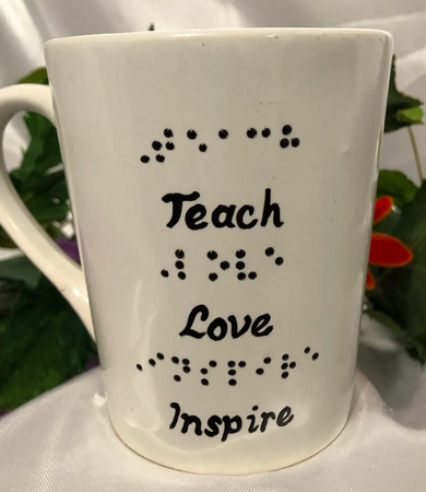 White 14oz. mug with words Teach Love Inspire in braille and script