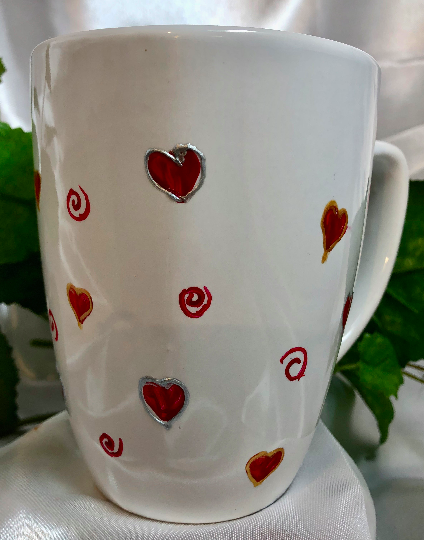 White ceramic mug  with hearts, outlined in raised gold outlining 
